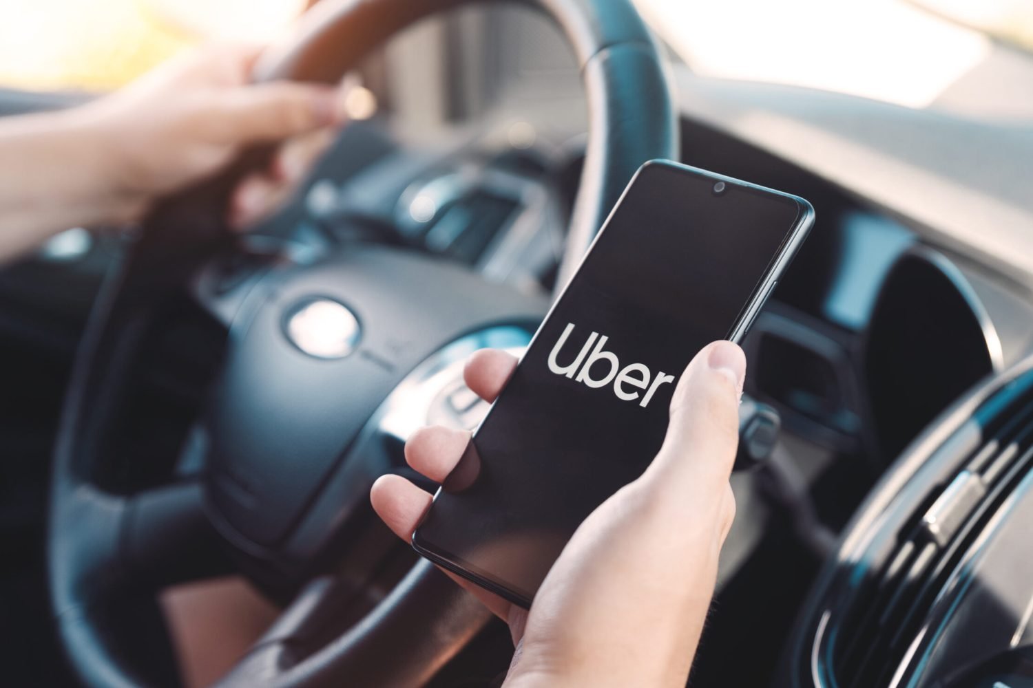 Wroclaw, Poland - AUG 25, 2020: Uber driver holding smartphone in car. Uber is sharing-economy service for ubran transport.